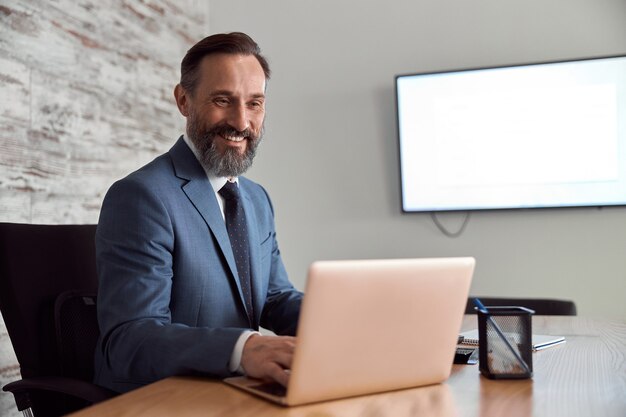 Foto homem adulto feliz trabalhando em um gabinete de escritório moderno