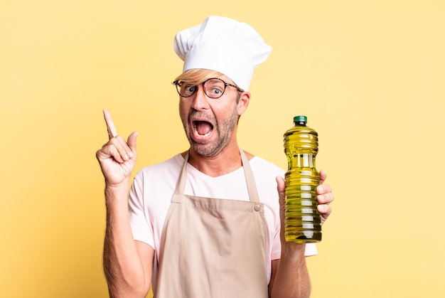 Homem adulto loiro bonito chef segurando uma garrafa de azeite