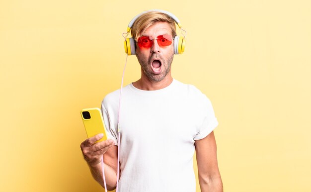 Homem adulto loiro parecendo muito chocado ou surpreso com fones de ouvido