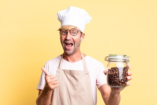 Homem adulto louro e bonito segurando uma garrafa de grãos de café