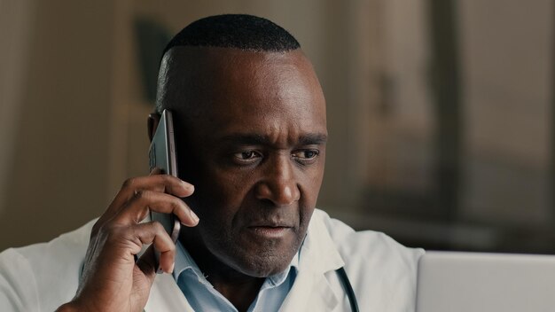 Homem adulto médico afro-americano trabalha com computador no hospital usa chamada de tecnologia médica moderna