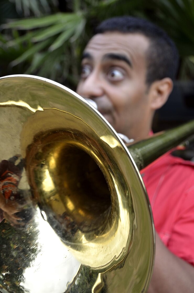 Foto homem adulto médio tocando saxofone enquanto está de pé contra as árvores