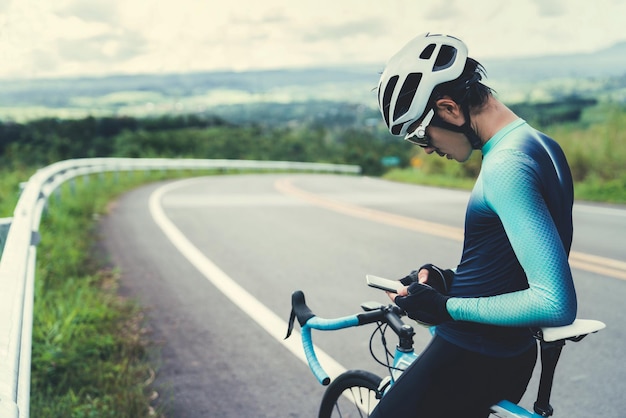 Foto homem adulto médio usando telefone sentado em bicicleta na estrada