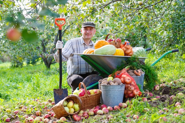 Homem adulto no jardim com uma rica colheita