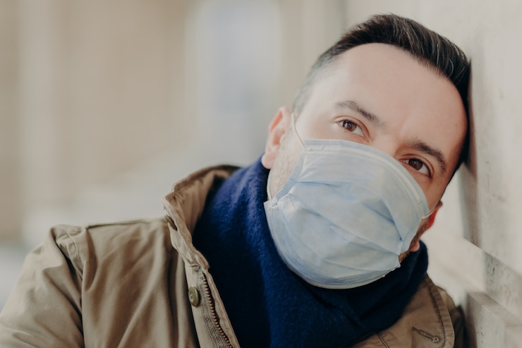Foto homem adulto pensativo caminha durante a epidemia de coronavírus, protege contra infecções, usa máscara médica