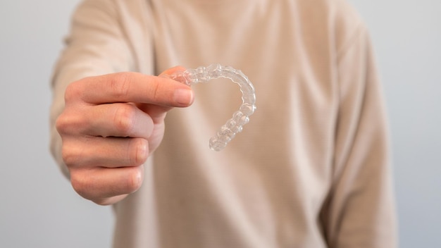 Homem adulto segura aparelho transparente invisalign para correção dentária pessoa caucasiana segurando retentor ortodôntico invisível e alinhador aparelhos plásticos odontologia para endireitar os dentes no consultório do dentista