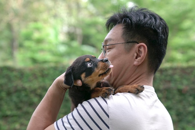 Homem adulto segurando cachorrinho no ombro