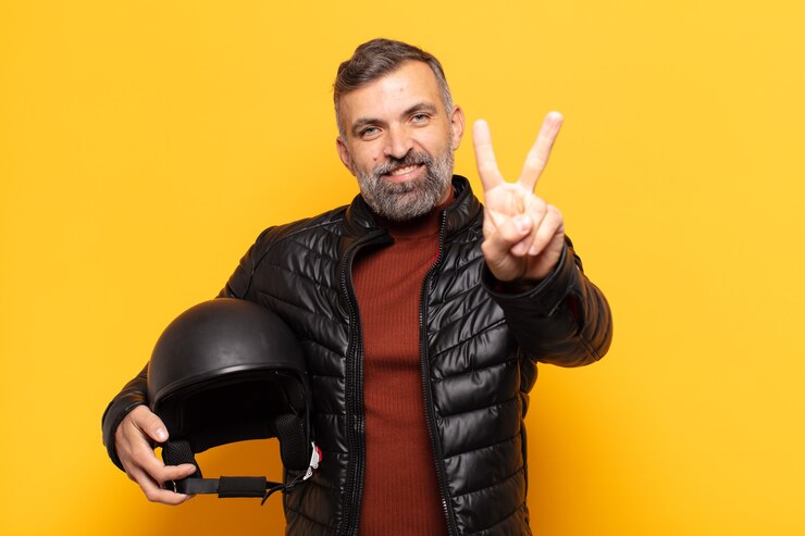 Foto homem adulto sorrindo e parecendo feliz, despreocupado e positivo, gesticulando vitória ou paz com uma das mãos