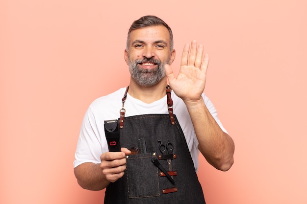 Homem adulto sorrindo feliz e alegremente, acenando com a mão, dando as boas-vindas e cumprimentando você ou dizendo adeus