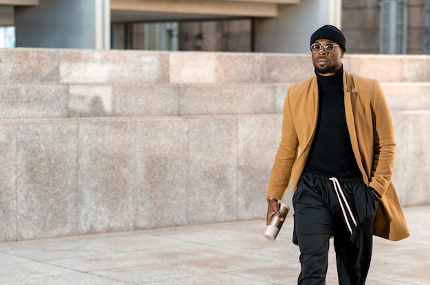 Homem africano atraente em um terno elegante, andando na cidade urbana.