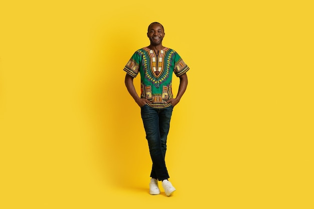 Homem africano atraente positivo em traje tradicional em amarelo
