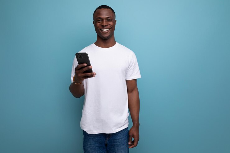 Homem africano bem preparado com corte de cabelo curto em camiseta branca com smartphone