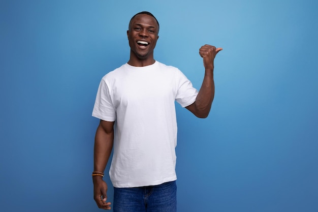 Homem africano bonito com corte de cabelo curto em camiseta branca mostra sua mão para o espaço