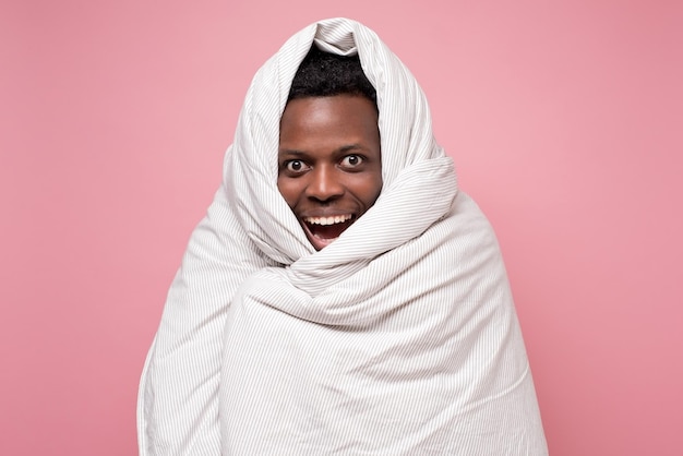 Homem africano bonito engraçado no cobertor branco descansando