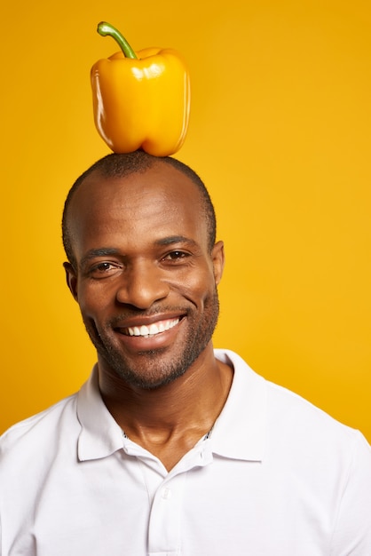 Homem africano com pimenta de sino amarelo sobre a cabeça que smilling.