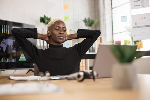 Foto homem africano confiante sentado relaxa no local de trabalho do escritório em casa tira uma soneca ou sonha acordado