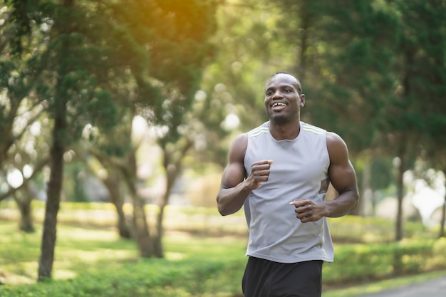 Homem africano correndo e sorrindo no parque pela manhã. Homem do esporte exercício no parque. Conceito de esporte