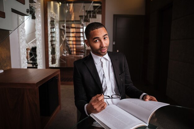 Foto homem africano de terno sentado à mesa com o diário no hotel