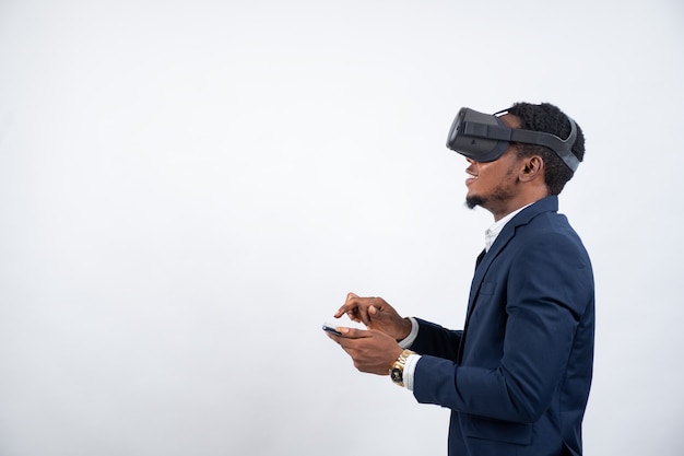 Homem africano de terno, usando fone de ouvido de realidade virtual e telefone