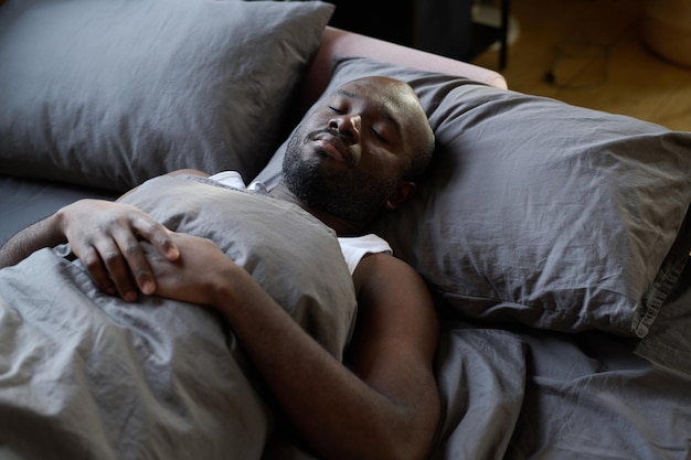 Homem africano dormindo em sua cama