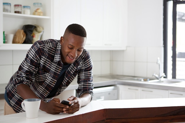 Foto homem africano, em, a, contador cozinha, usando, telefone móvel