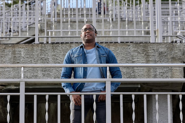 Homem africano em uma camisa jeans azul olha para os arredores andando sozinho