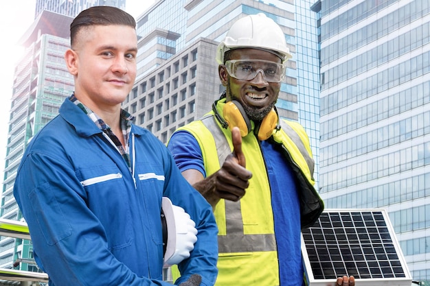 Homem africano, engenheiro de fábrica, com painel de célula solar em pé na frente da fachada do prédio
