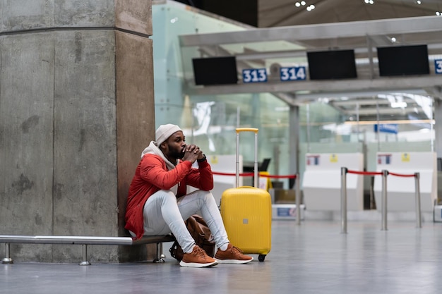 Homem africano exausto em uma longa conexão noturna no aeroporto esperando um avião sentado no terminal