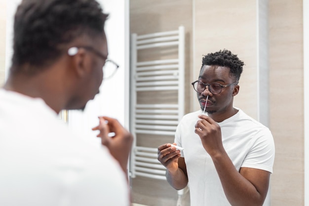 Homem africano fazendo autoteste para COVID19 com kit de teste de antígeno Coronavirus teste de zaragatoa nasal
