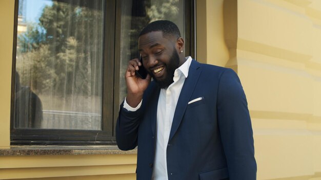 Homem africano feliz andando na rua Jovem empresário falando no celular