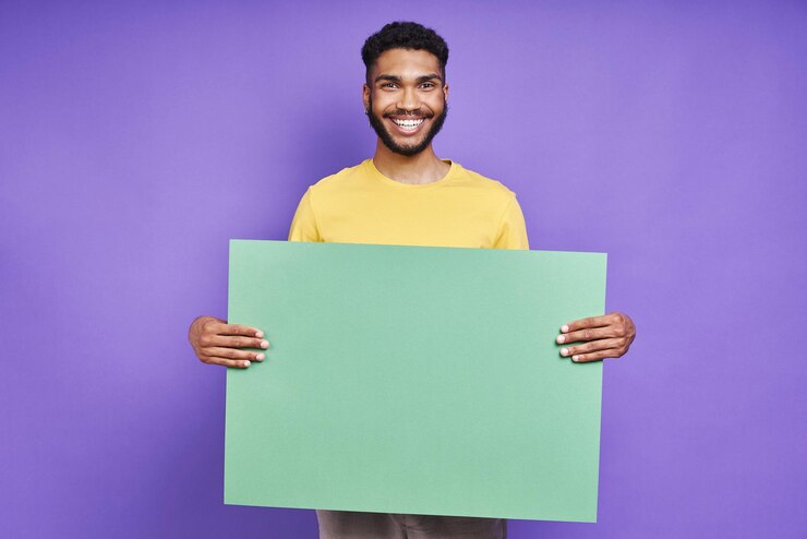 Foto homem africano feliz segurando uma bandeira verde enquanto está de pé contra um fundo roxo