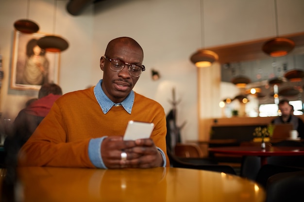 Homem Africano moderno usando Smartphone no café