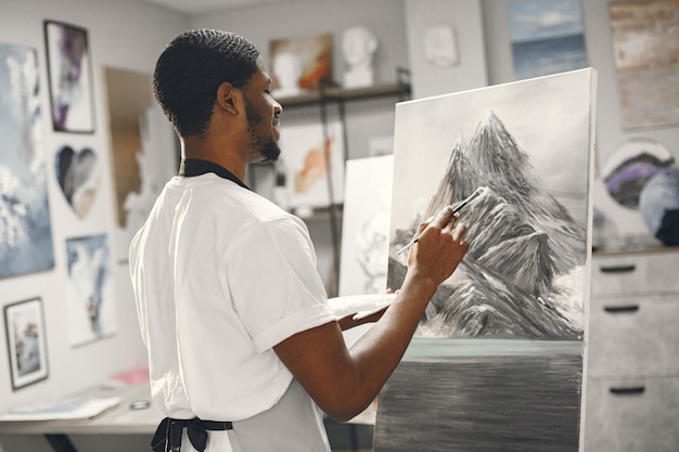 Homem africano na aula de pintura de desenho em um cavalete.