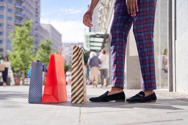 Homem africano na moda pegando sacolas de compras do chão