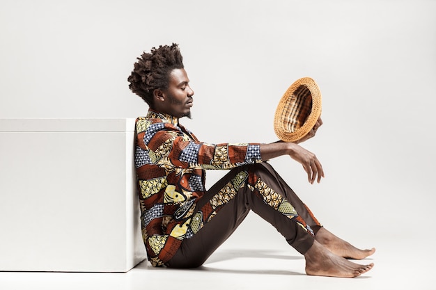 Foto homem africano pensativo olhando no chapéu e meditando. interior, isolado em fundo cinza