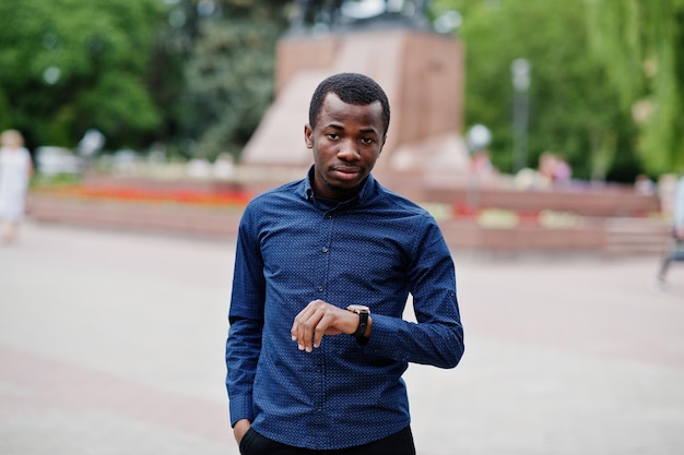 Homem africano posou na rua da cidade vestindo camisa azul e calça preta