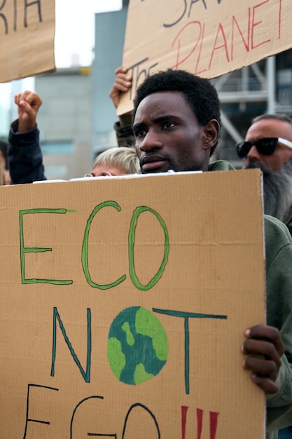 Foto homem africano sério segurando uma bandeira em uma manifestação pessoas em manifestação sobre a mudança climática