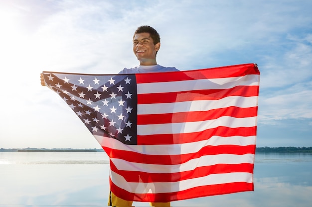 Homem afro-americano a desviar o olhar e a segurar com orgulho a bandeira americana