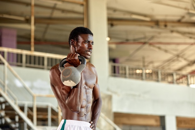 Homem afro-americano atraente sorrindo e fazendo exercícios com halteres