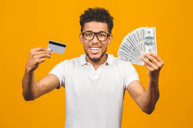 Homem afro-americano barbudo bonito casual segurando uma pilha de dinheiro e um cartão de crédito