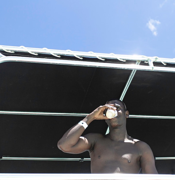 Homem afro-americano bebendo no gazebo da praia