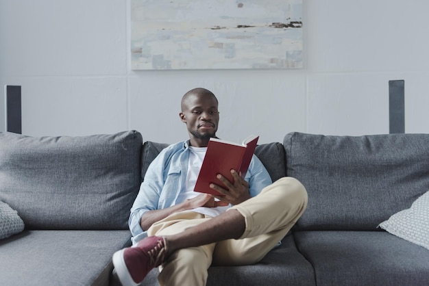 Homem afro-americano bonito lendo livro em casa