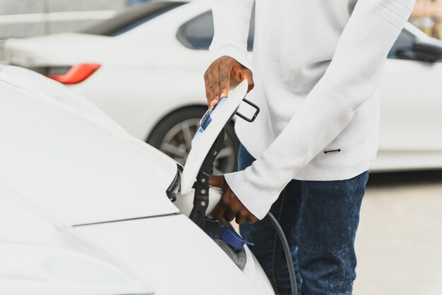 Homem afro-americano carregando seu carro elétrico.