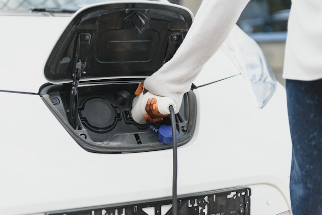 Homem afro-americano carregando seu carro elétrico.