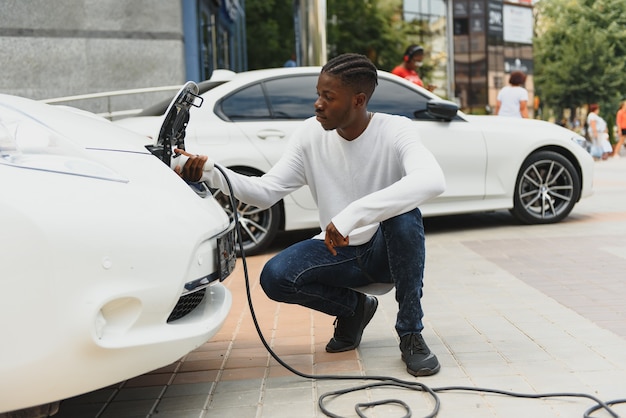 Homem afro-americano carregando seu carro elétrico.