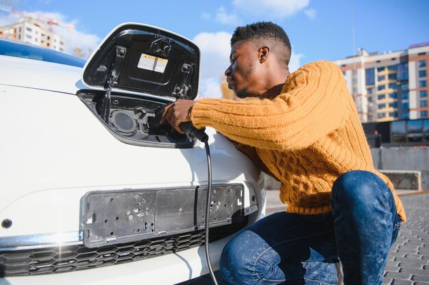 Homem afro-americano carregando seu carro elétrico.