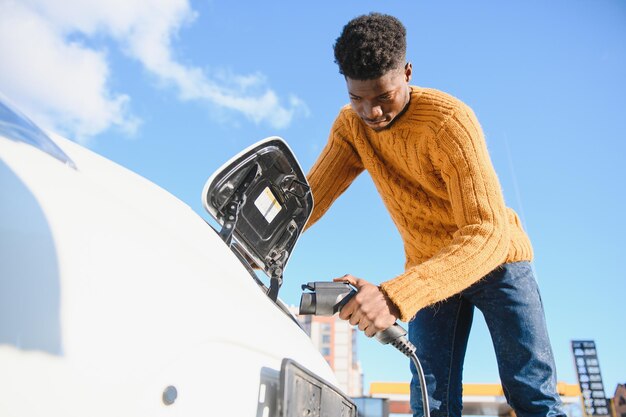 Homem afro-americano carregando seu carro elétrico.