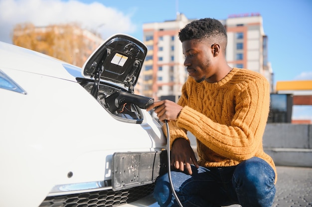 Homem afro-americano carregando seu carro elétrico.