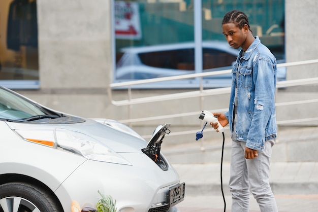 Homem afro-americano carregando seu carro elétrico.