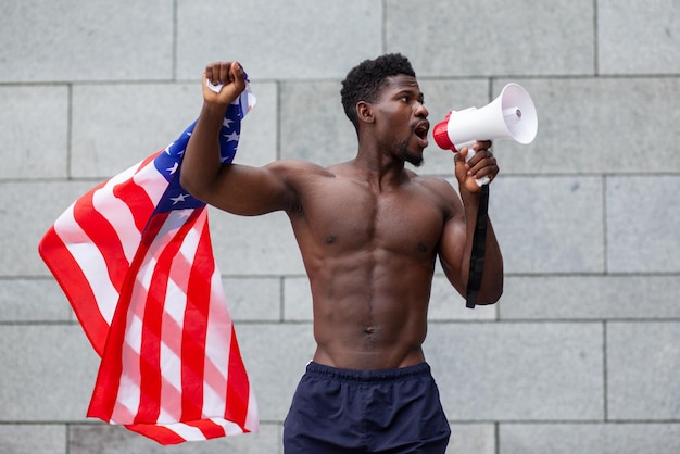 Homem afro-americano com a bandeira dos eua grita em um megafone e protesta